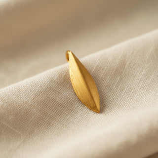 Gold leaf pendant on a beige fabric surface